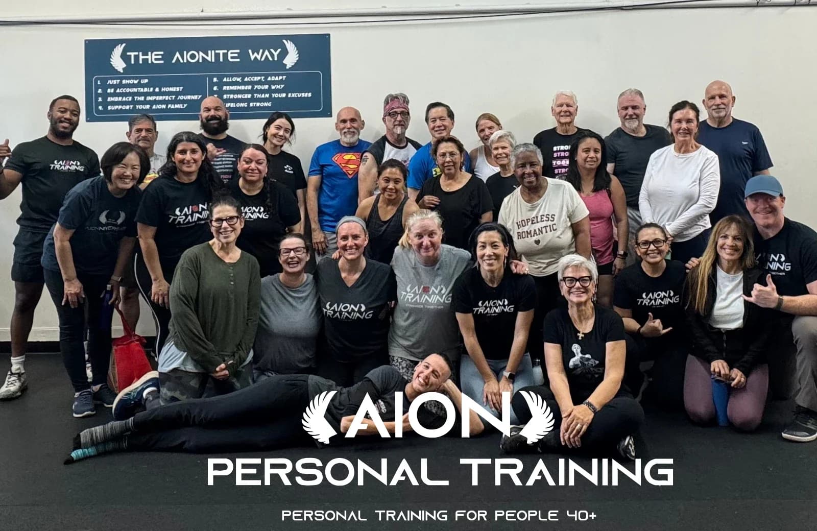 A large group of members and coaches gathered in the studio in front of the Aionite Way board.