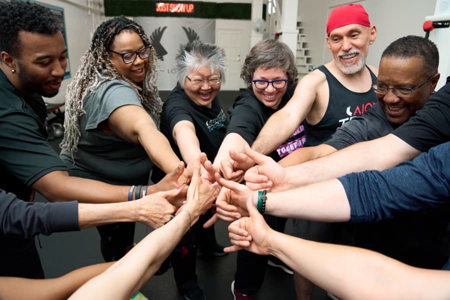 Members and coaches stack their hands in a circle in the middle of the studio.